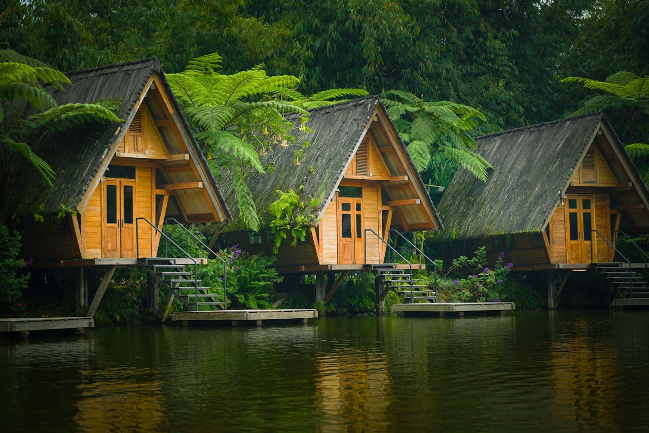 Picturesque wooden huts on a serene lake surrounded by lush greenery in West Java, Indonesia.